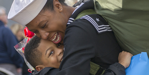 Navy woman hugging child.