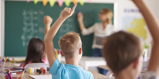 Children in classroom raising their hands.