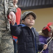 Military child holds father's hand.
