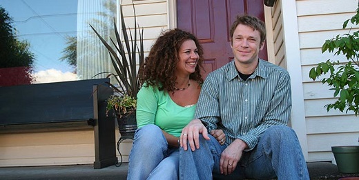 Couple sitting and smiling on front porch.