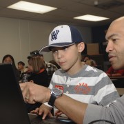 A man shows a boy how to use a computer.