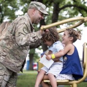 National Guard service member and family play on playground. 