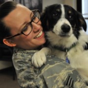 U.S. service member hugs dog in her arms.