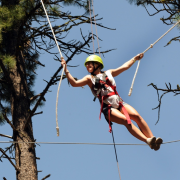 A woman hangs from a zipline in the trees.