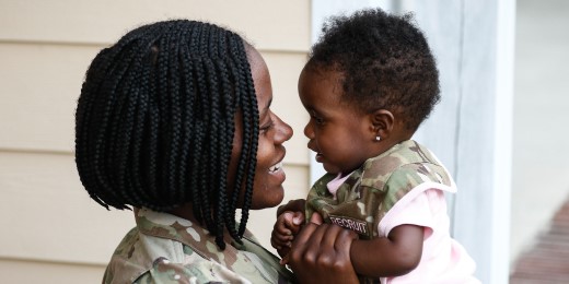 Service member embraces young daughter.