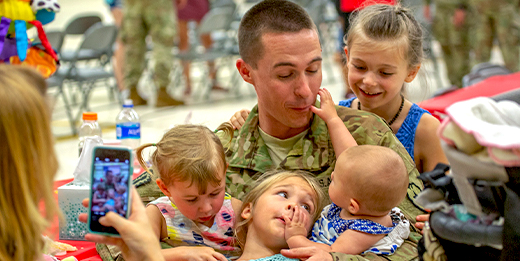 Service member hugs and plays with his family