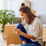 Woman sitting by moving boxes on phone