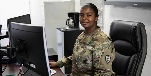 Military service woman sits at computer