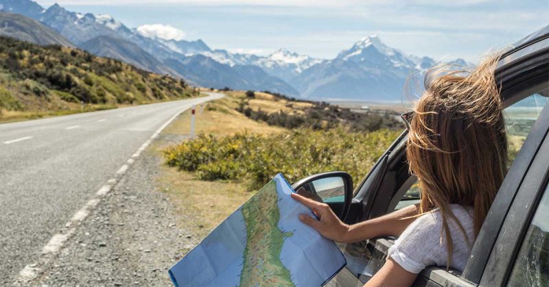 A woman pulled over on the side of the road, looking at the mountains