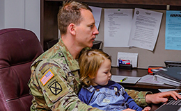 Service member with child on computer
