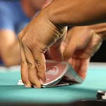 Hands shuffling cards on table with poker chips