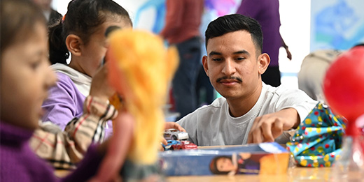 Navy officer plays with child during community support event