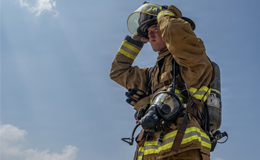 Service member posing with firefighter gear