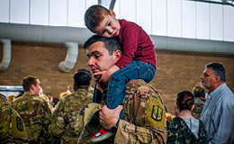 Child sitting on service member's shoulders