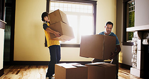 Child helping father with moving boxes.