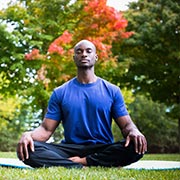 Young man meditating on a yoga mat outside