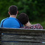 Spouses leaning on each other on bench