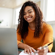 Woman smiling at laptop while writing