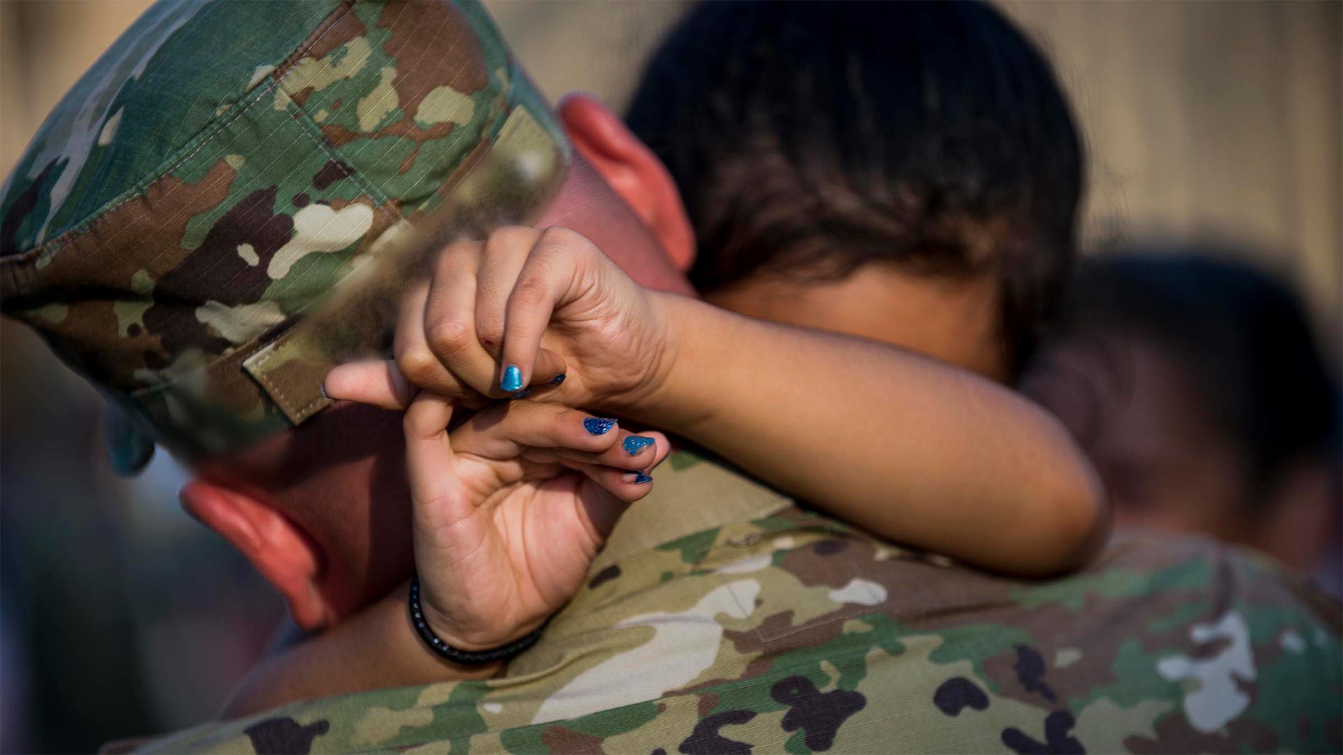 Child hugging service member