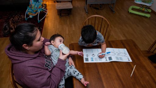 Mother feeding baby with toddler nearby