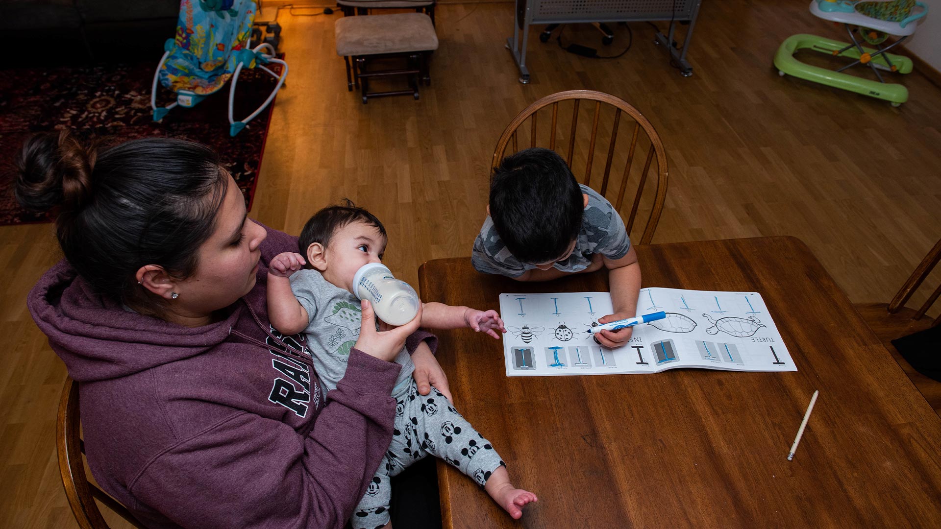 Mother feeding baby with toddler nearby