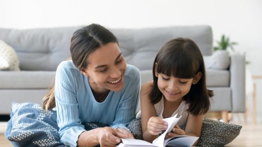 Smiling mother and daughter read together