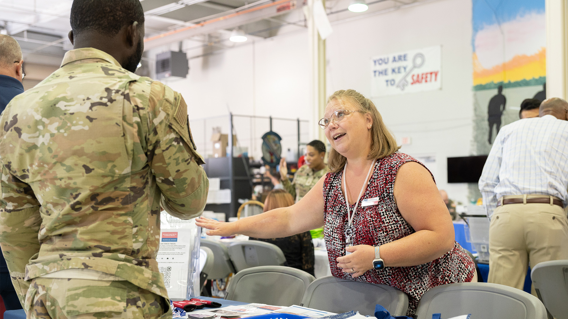 State consultant talking with service member at booth