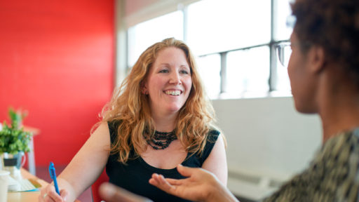 Smiling woman takes notes during a conversation