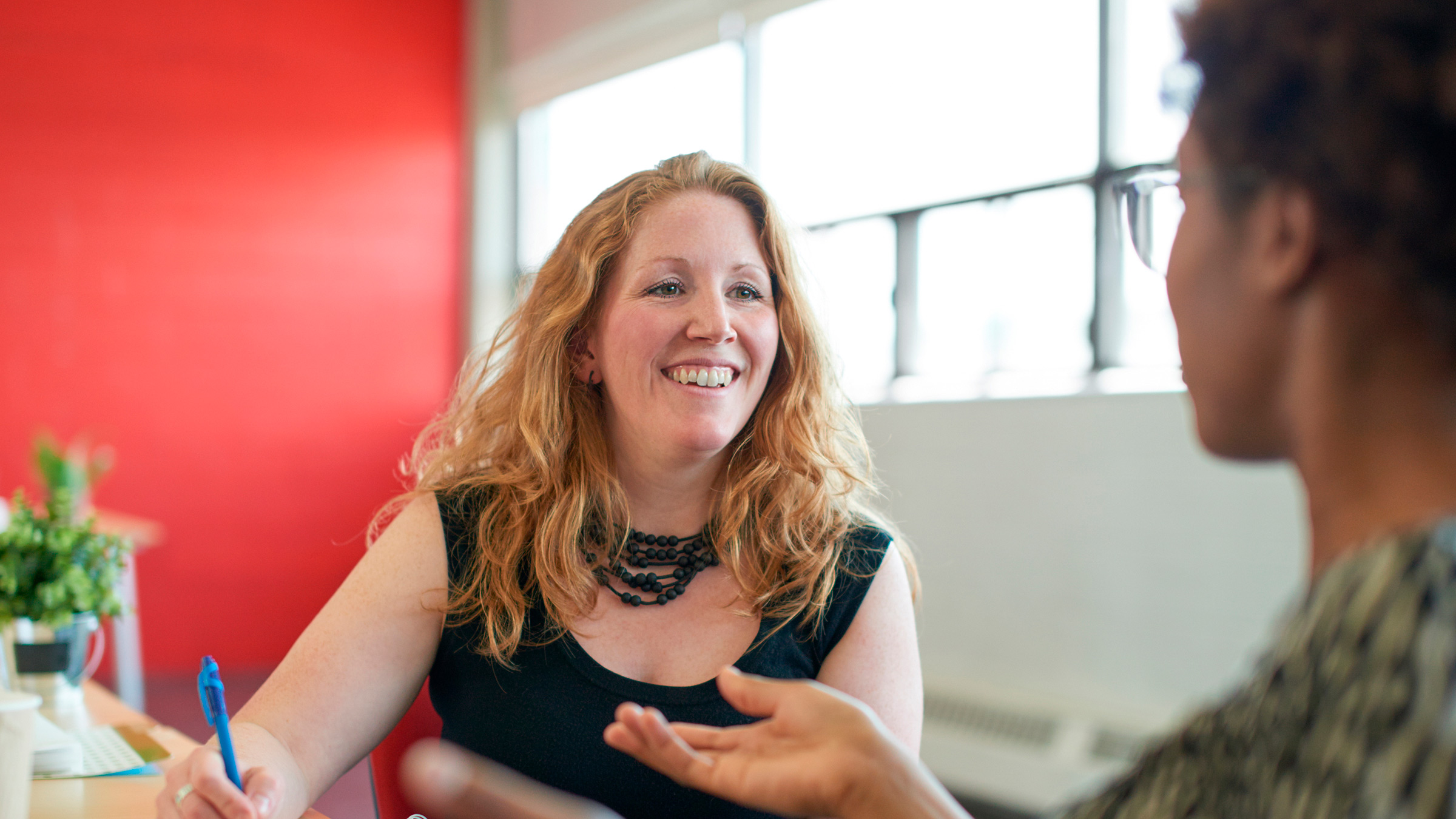 Smiling woman takes notes during a conversation