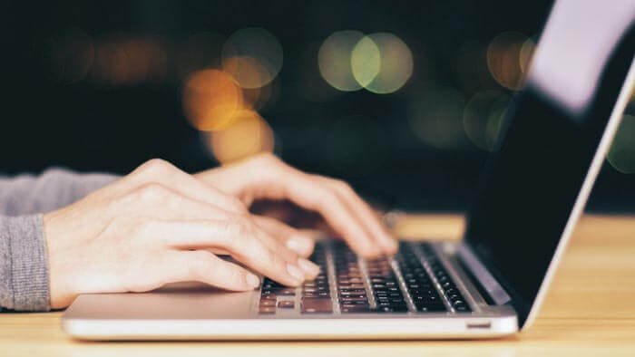 Hands typing on a laptop computer