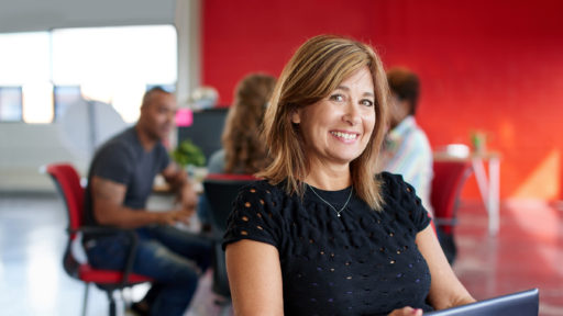 Woman smiles, while others work in the background