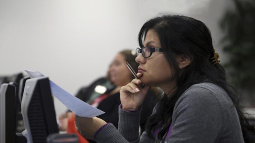 Woman with papers in hand listening to speaker