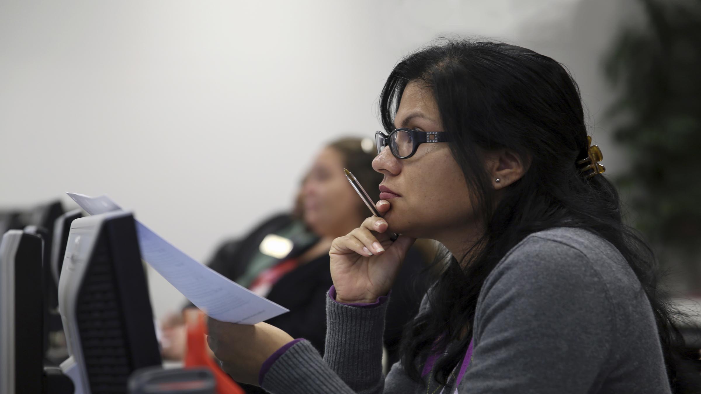 Woman with papers in hand listening to speaker