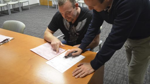 Man helping another man with filing paperwork