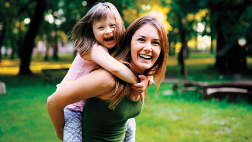 mother holding little girl with special needs on her back 