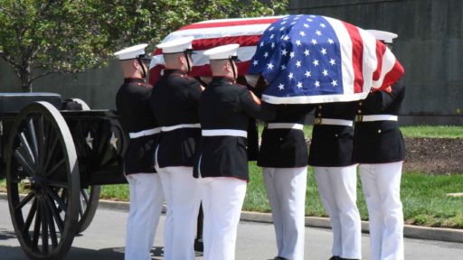 Marines carry flag-covered casket.
