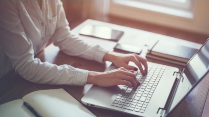 Hands typing on a laptop computer