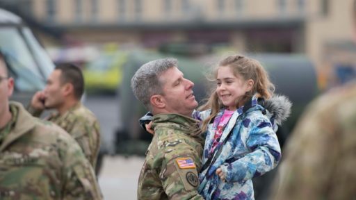 A service member greets his young daughter