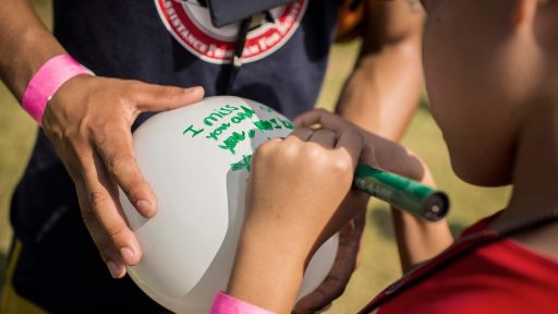 child writes message on balloon