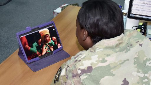 A service member watches her children open presents via video chat.