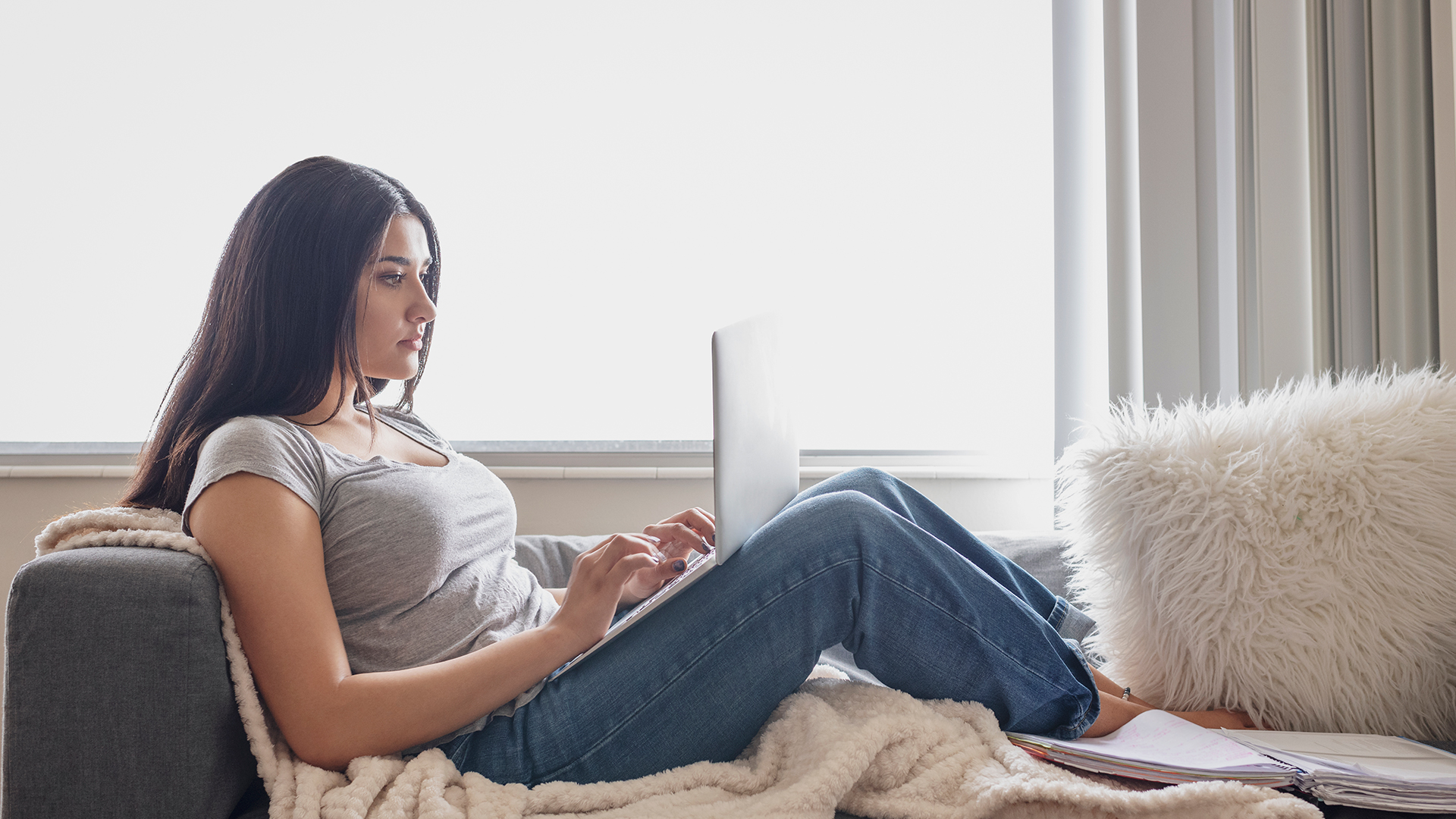 Young woman relaxing on sofa with laptop