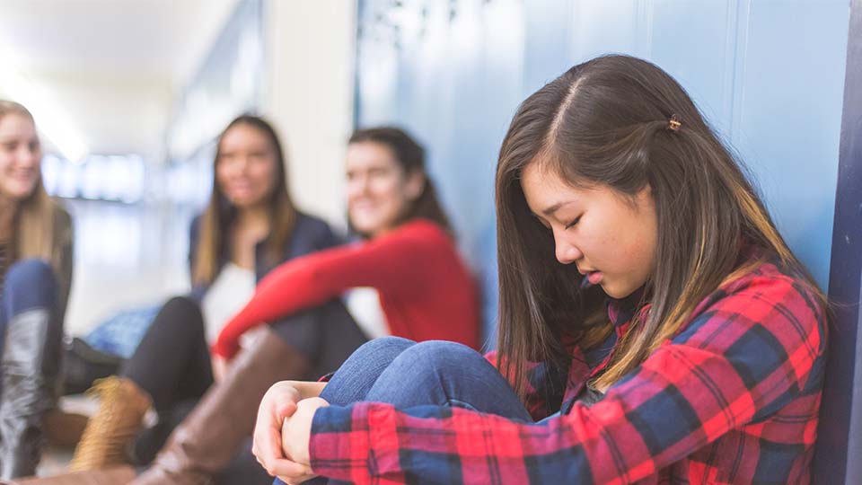 Sad girl sits by lockers