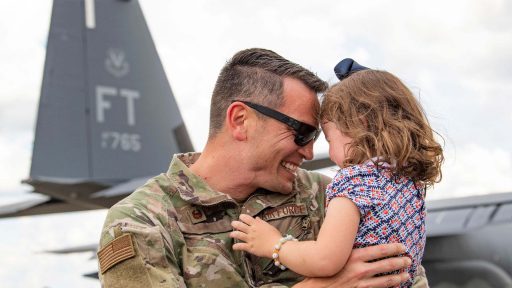 Military dad smiles while holding daughter