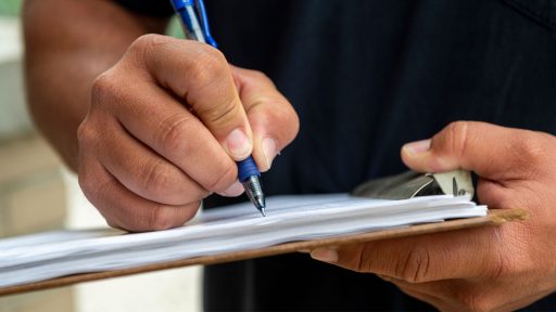 Hands holding clipboard and signing paperwork