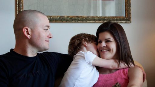 Family sitting on couch with child hugging mother