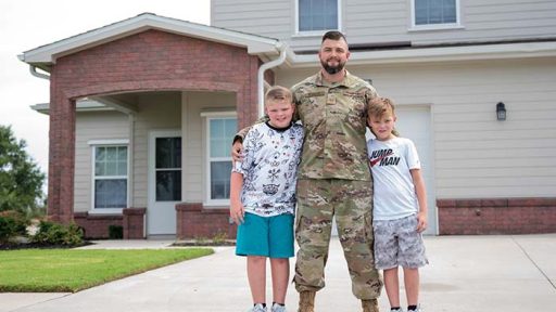 military family standing in front of home