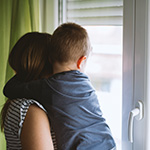 mom holds child looking out window
