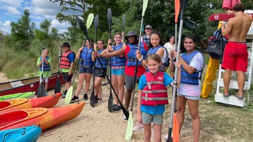kids holding oars near canoes