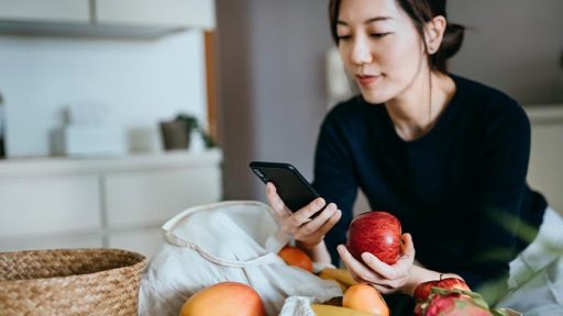 person on phone holding apple
