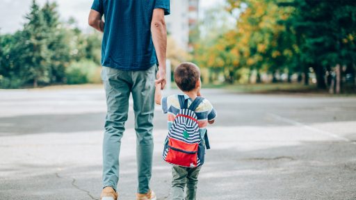 Father holds child’s hand while walking